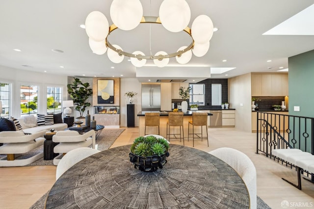 dining room with a large fireplace, light wood-style floors, and recessed lighting