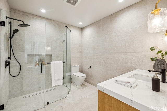 full bath featuring a stall shower, visible vents, toilet, vanity, and tile walls