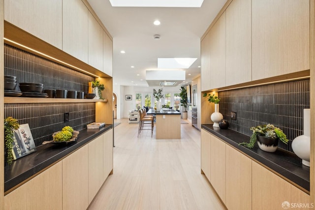 interior space featuring dark countertops, a skylight, modern cabinets, and light wood-style flooring