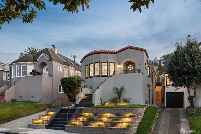 mediterranean / spanish-style home featuring a garage, driveway, stairway, and stucco siding