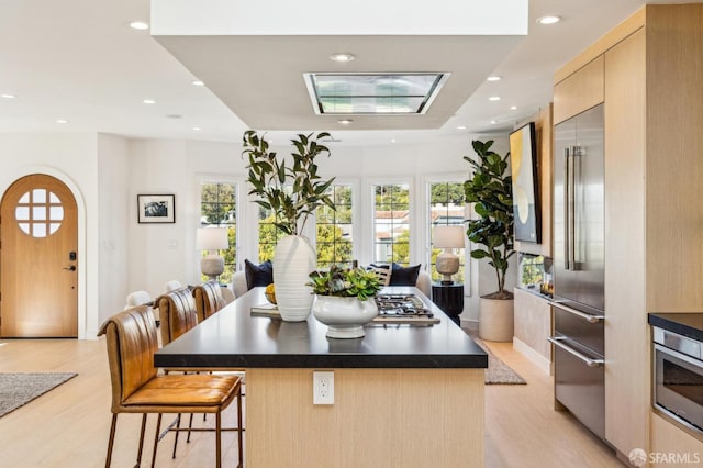 kitchen featuring dark countertops, modern cabinets, built in fridge, and a kitchen breakfast bar