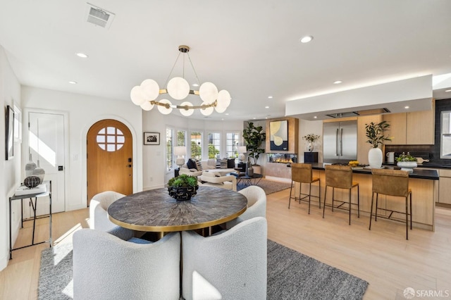 dining area with visible vents, arched walkways, an inviting chandelier, light wood-type flooring, and recessed lighting