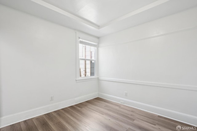 spare room with baseboards and wood finished floors