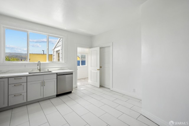 kitchen with gray cabinets, dishwasher, a sink, light countertops, and baseboards
