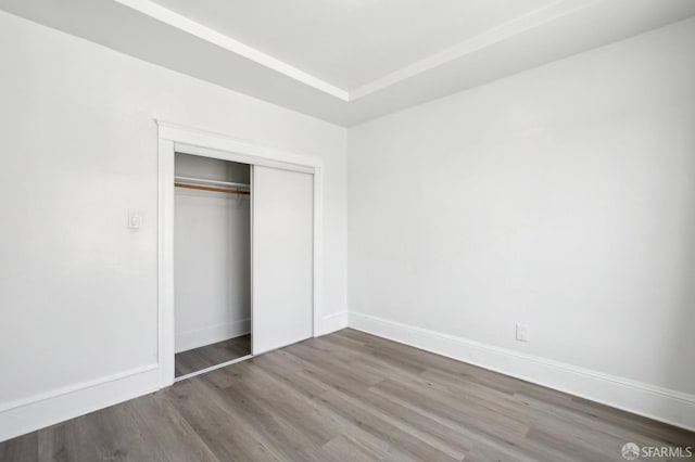 unfurnished bedroom featuring baseboards, a closet, and wood finished floors