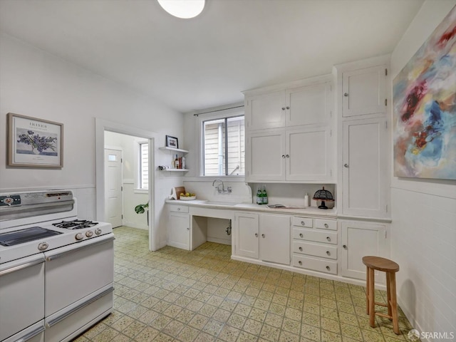 kitchen with sink, white cabinets, and range with two ovens