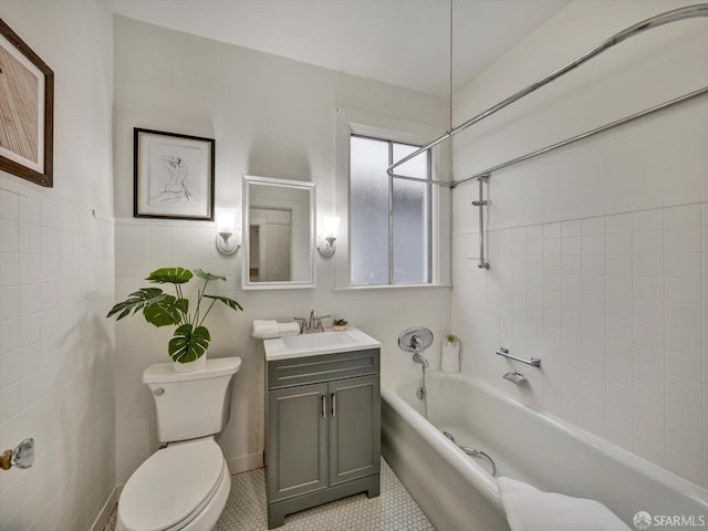 bathroom featuring a washtub, tile walls, vanity, tile patterned floors, and toilet