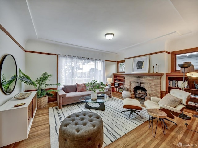 living room with a brick fireplace and light wood-type flooring