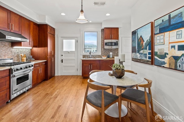 221 Noe St Unit 12, San Francisco, CA 94114 - kitchen featuring stainless steel appliances, under cabinet range hood, light countertops, decorative backsplash, and light wood-style floors
