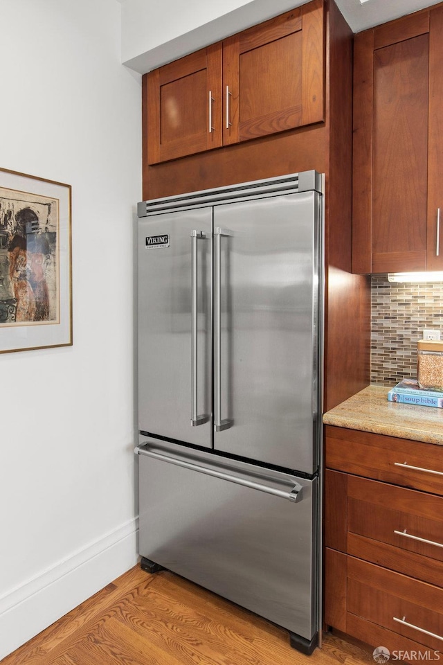 221 Noe St Unit 12, San Francisco, CA 94114 - kitchen featuring high end fridge, decorative backsplash, brown cabinets, and light wood finished floors
