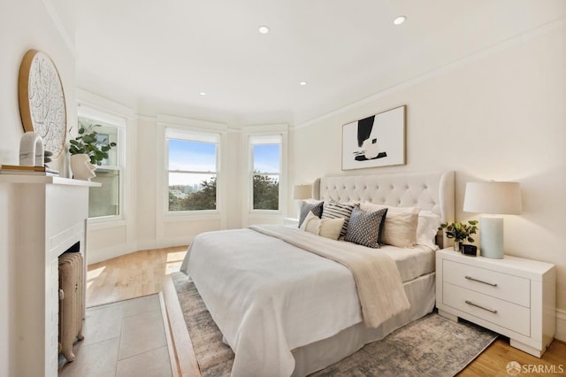 bedroom with light wood-type flooring, radiator, and ornamental molding