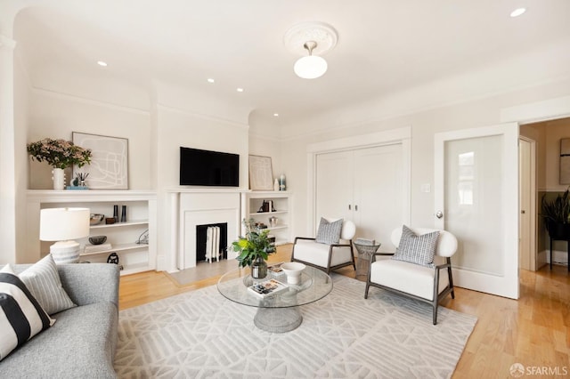 living room with built in shelves and light wood-type flooring