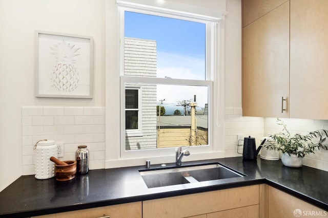 kitchen featuring light brown cabinetry, sink, and backsplash