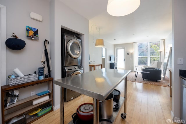 kitchen with stacked washer and clothes dryer, decorative light fixtures, and light hardwood / wood-style floors