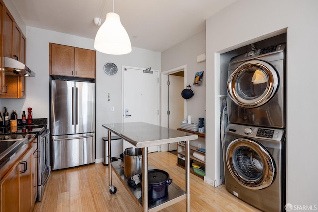 interior space with stacked washer and clothes dryer, stainless steel appliances, pendant lighting, and light hardwood / wood-style flooring