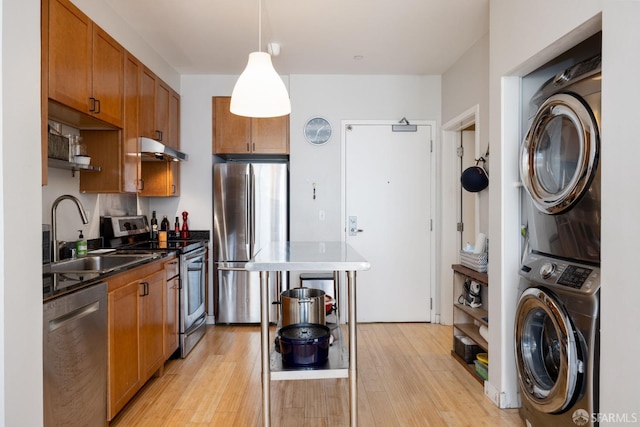 kitchen featuring light hardwood / wood-style flooring, stainless steel appliances, sink, and stacked washing maching and dryer