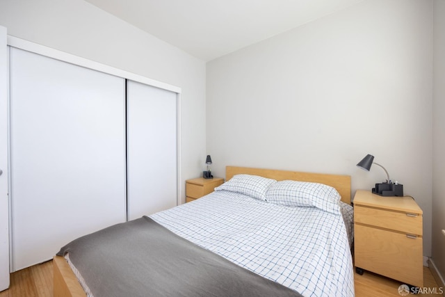 bedroom with light hardwood / wood-style floors and a closet