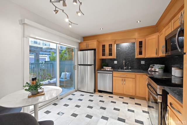 kitchen with glass insert cabinets, dark countertops, appliances with stainless steel finishes, and decorative backsplash