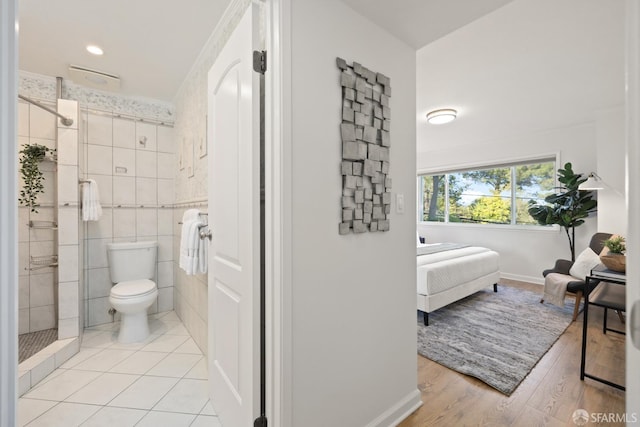 full bath featuring a shower stall, baseboards, toilet, wood finished floors, and tile walls