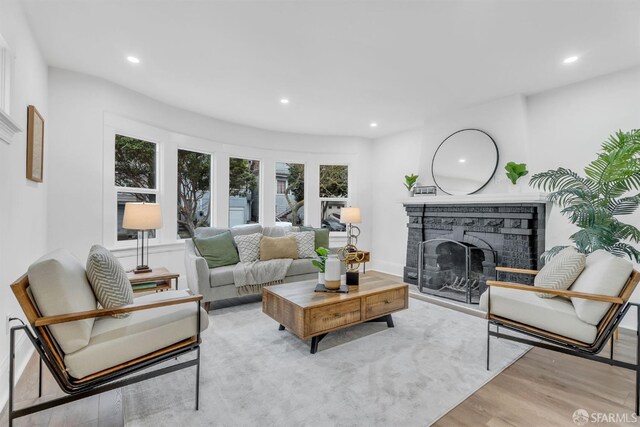 living area with baseboards, a stone fireplace, wood finished floors, and recessed lighting