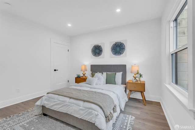 bedroom with baseboards, wood finished floors, and recessed lighting