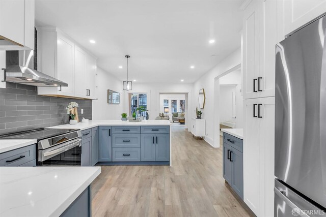 kitchen with stainless steel appliances, light wood finished floors, a peninsula, and white cabinetry