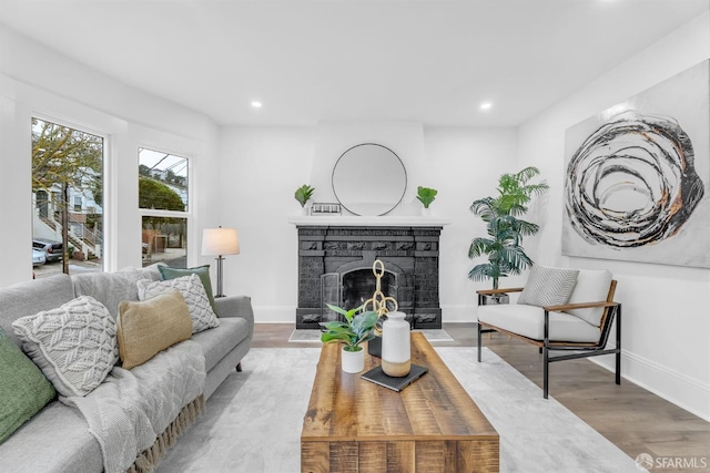 living room featuring a fireplace, baseboards, wood finished floors, and recessed lighting