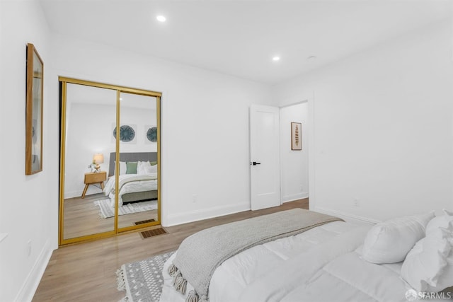 bedroom featuring visible vents, baseboards, light wood-style floors, a closet, and recessed lighting