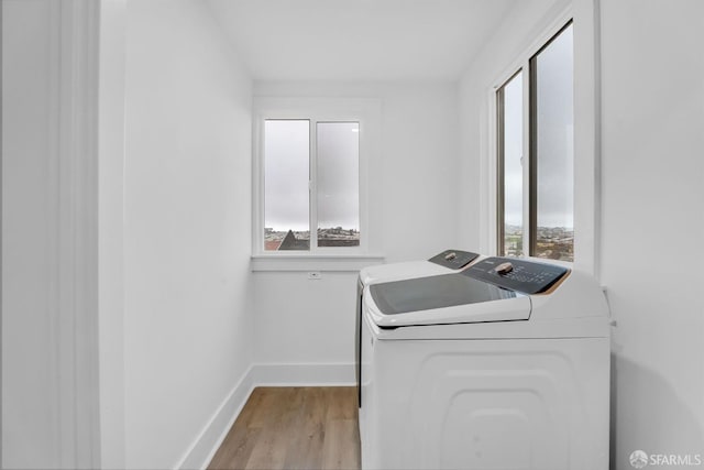 laundry room featuring laundry area, separate washer and dryer, wood finished floors, and a wealth of natural light