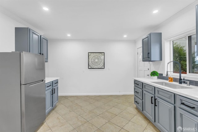 kitchen featuring recessed lighting, a sink, baseboards, light countertops, and freestanding refrigerator