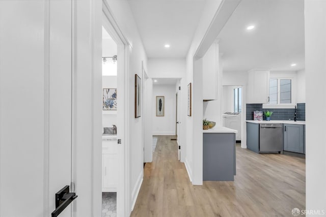 hallway with light wood finished floors, baseboards, and recessed lighting