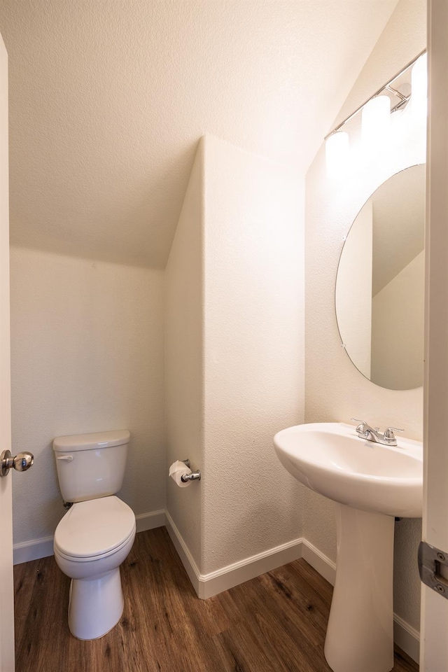 bathroom featuring sink, hardwood / wood-style floors, lofted ceiling, and toilet