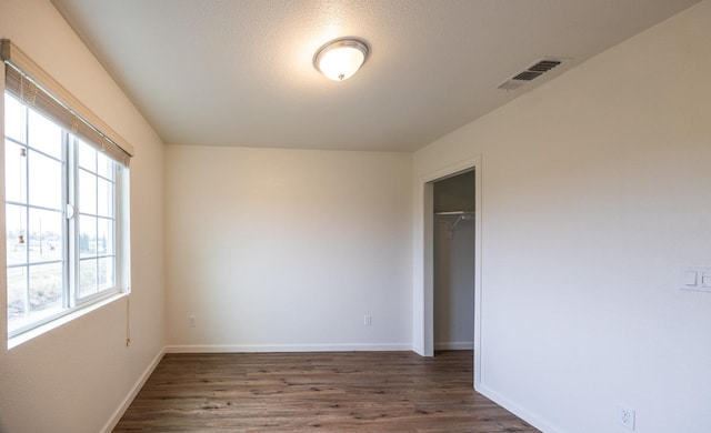 spare room featuring a textured ceiling, a wealth of natural light, and dark hardwood / wood-style floors