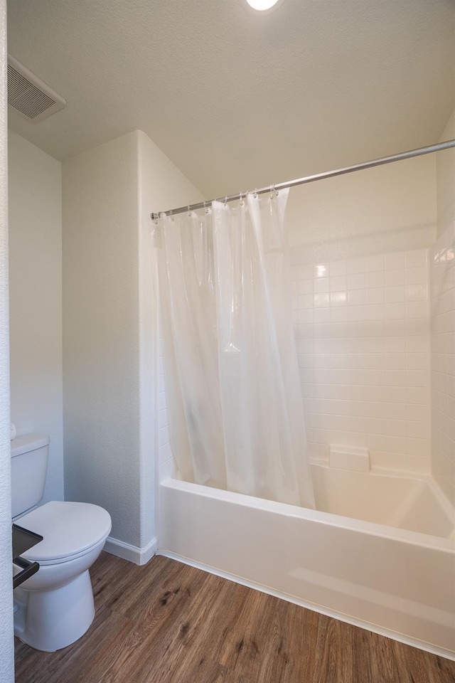 bathroom with hardwood / wood-style floors, toilet, and shower / bath combo