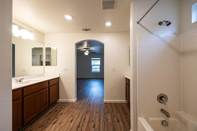 bathroom featuring vanity, washtub / shower combination, ceiling fan, a textured ceiling, and wood-type flooring