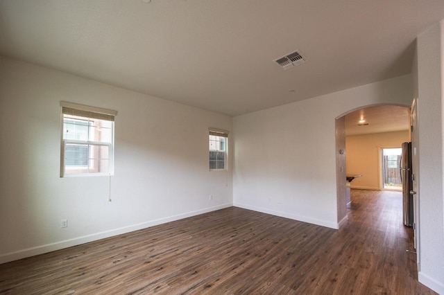 spare room featuring dark wood-type flooring and a wealth of natural light