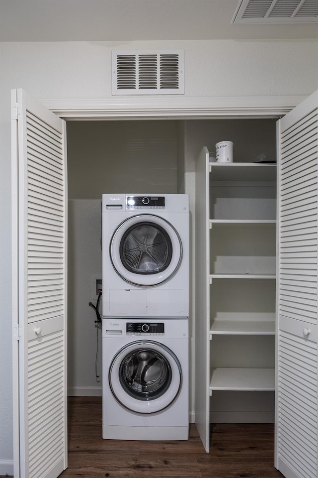 clothes washing area with stacked washer / dryer and dark hardwood / wood-style floors