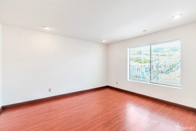 unfurnished room with baseboards and wood finished floors