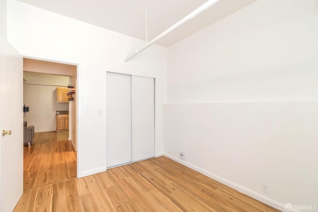 unfurnished bedroom with light wood-style flooring, a closet, and baseboards
