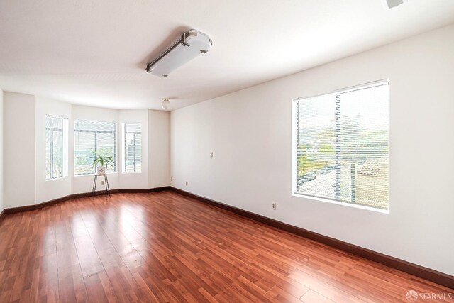 spare room featuring baseboards and wood finished floors