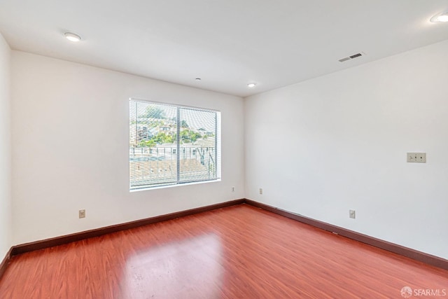unfurnished room featuring wood finished floors, baseboards, and recessed lighting