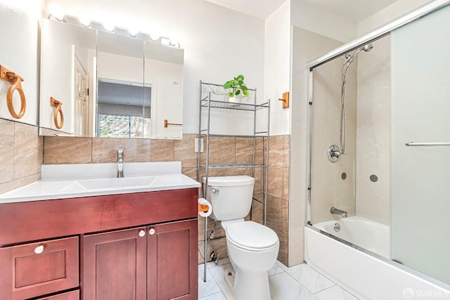 bathroom with tile walls, toilet, vanity, enclosed tub / shower combo, and a wainscoted wall
