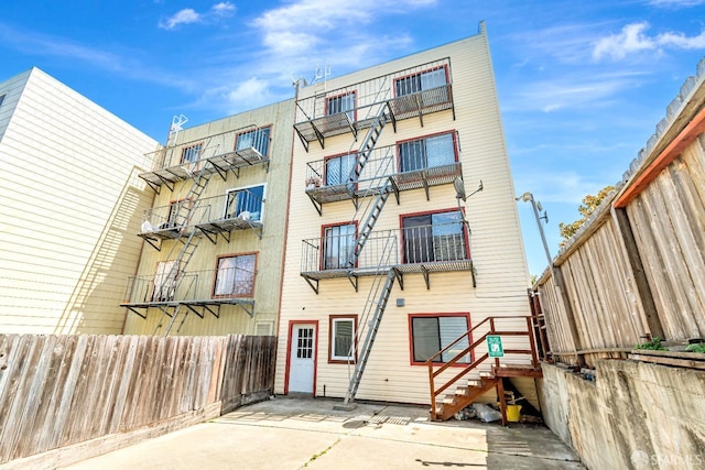 view of apartment building / complex featuring fence and stairway