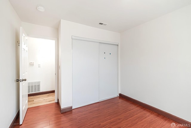 unfurnished bedroom featuring wood finished floors, a closet, and baseboards