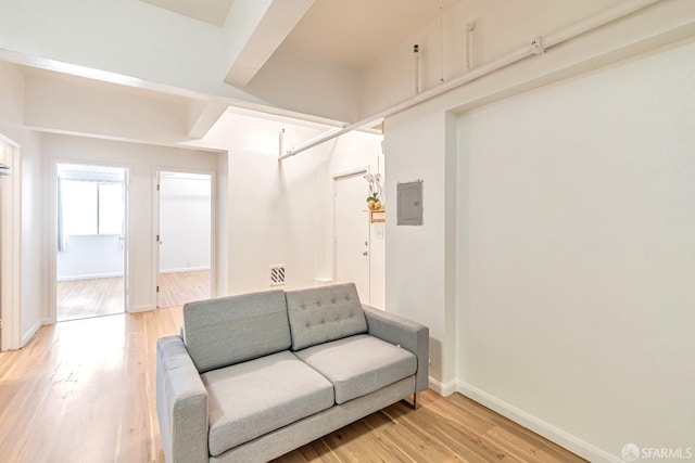 living area featuring light wood-style floors, baseboards, and electric panel