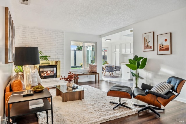 sitting room with a textured ceiling, a fireplace, baseboards, and wood finished floors