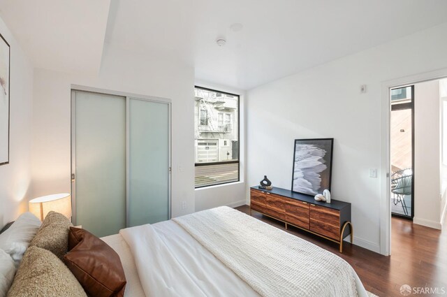 bedroom featuring dark wood-style floors, a closet, and baseboards