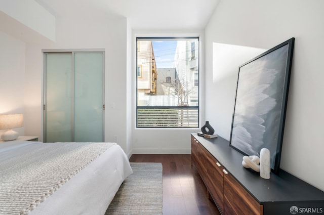 bedroom featuring a closet, baseboards, and dark wood-style flooring