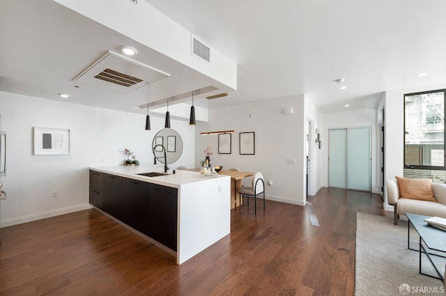 kitchen featuring dark wood-style floors, light countertops, visible vents, a sink, and a peninsula