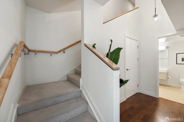 stairs featuring lofted ceiling, wood finished floors, and baseboards